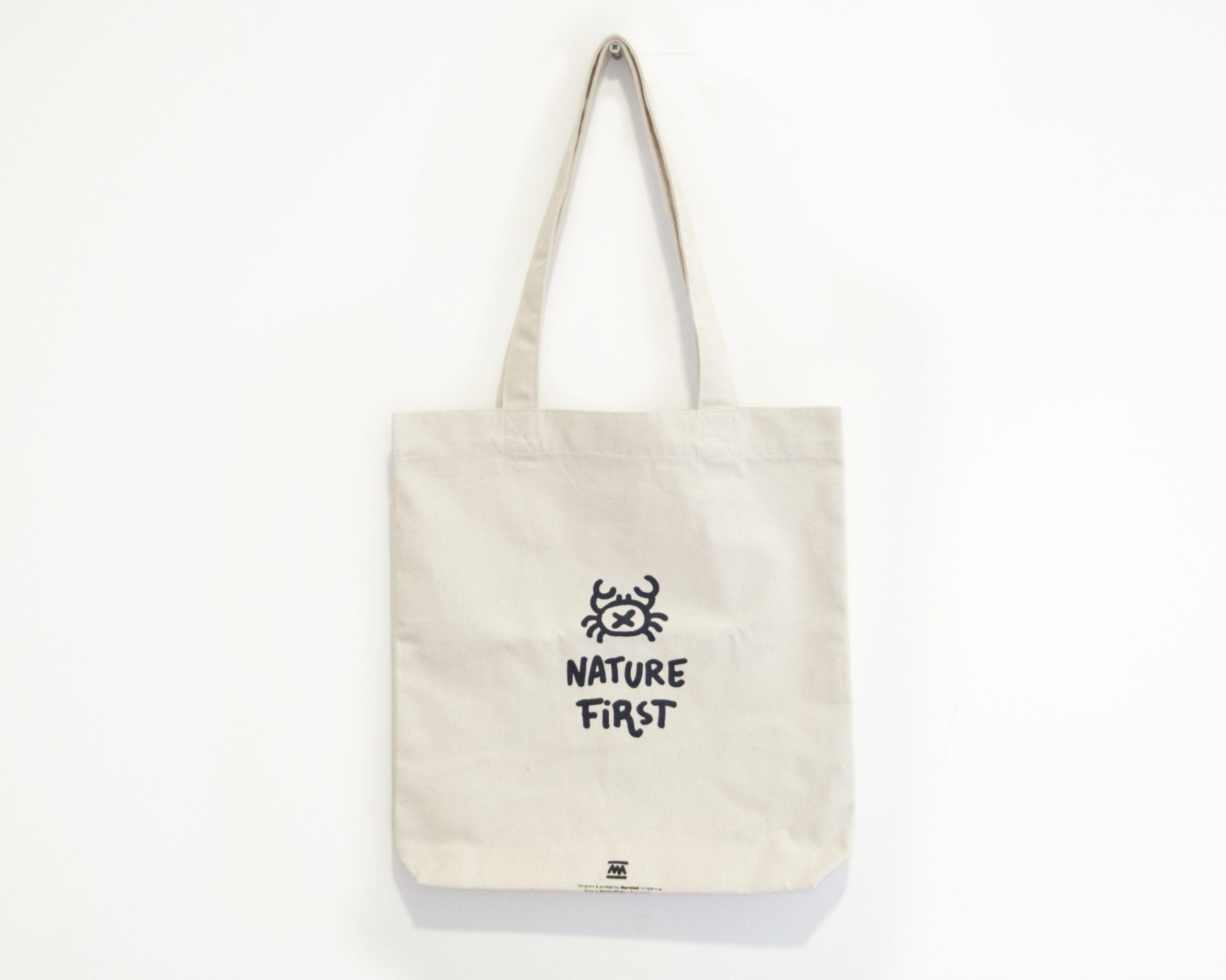 Borsa tote bianca naturale della collezione Nature First - Illustrazione originale con un design minimalista di un granchio di sabbia - Realizzata con certificazione Fair Trade e cotone biologico riciclato. Design ispirati alla natura per una moda sostenibile. Prodotta in Spagna.